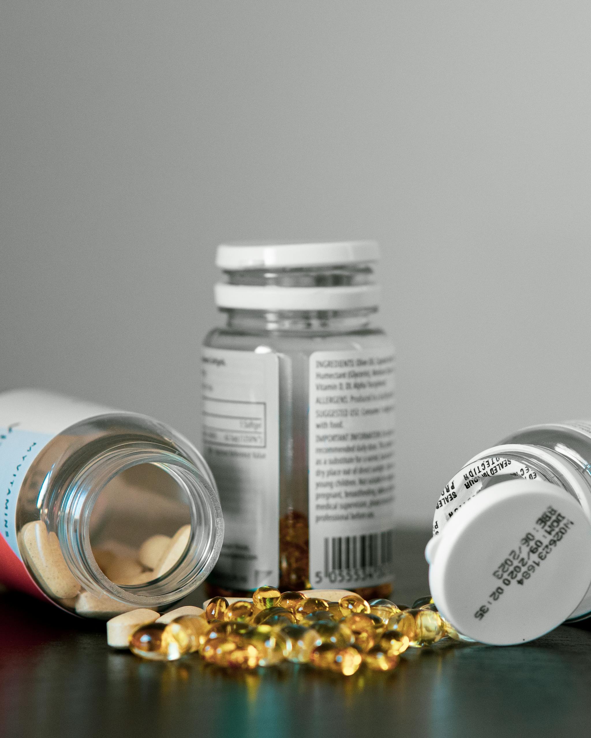 Close-up of various pill bottles and vitamins spilled on a table.